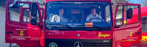 Feuerwehrauto der Werkfeuerwehr mit zwei Teilnehmern des Boys Day
