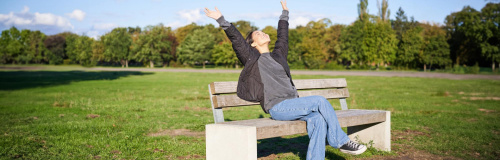 Freudige Frau auf einer Bank in der Wiese