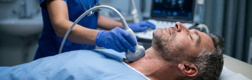 Mann der mit einem Ultraschallgerät an der Schilddrüse untersucht wird