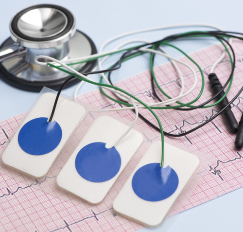 Elektronen liegen auf einem EKG-Papier neben einem Stethoskop 